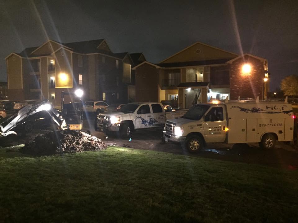 Holman's Quality Plumbing trucks and excavation equipment working at night